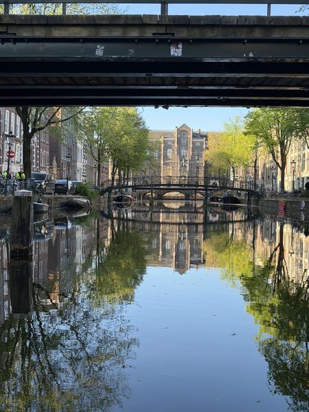 This photo captures a serene view of the Lommertbrug in Centrum, Amsterdam, showcasing the tranquil canal with its reflections